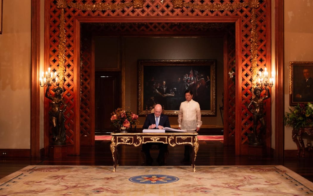 Prime Minister Christopher Luxon signs documents at the Philippines Presidential Palace in Manila.
