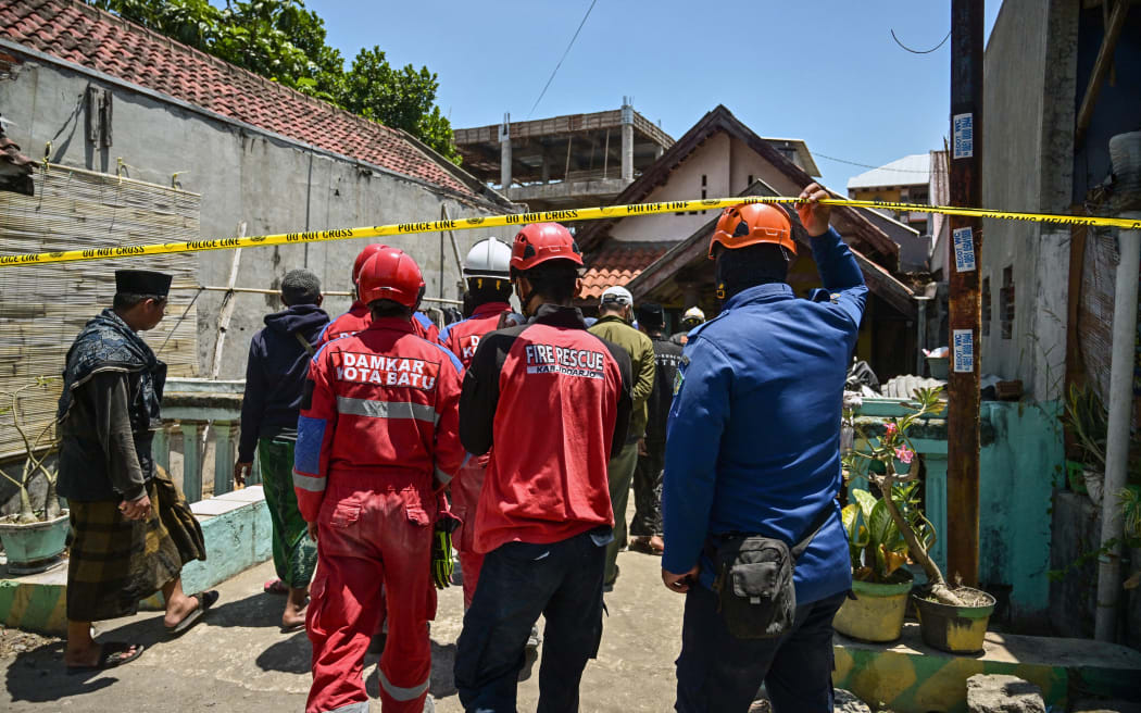 Rescuers walk in the cordoned off area at the Al Khoziny Islamic boarding school in Sidoarjo, East Java province on October 2, 2025, after a multi-storey building at the school collapsed. Rescuers detected "no more signs of life" under the rubble of a collapsed Indonesian school where 59 people remain missing, an official said on October 2, raising fears of a high death toll. (Photo by Juni KRISWANTO / AFP)