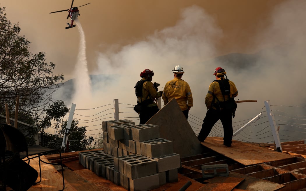 A firefighting helicopter drops water on the Palisades Fire on January 11, 2025 in Los Angeles, California. The Palisades fire had grown to over 22,000 acres and has destroyed thousands of homes. The fire is currently 11 percent contained