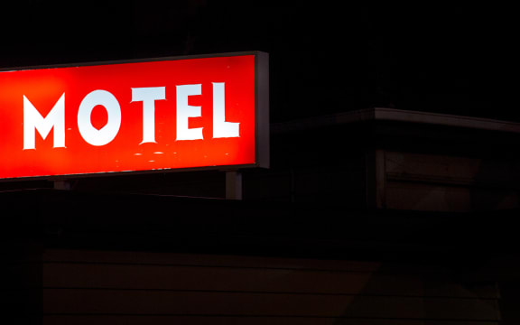 A worn motel sign lit up at night in Otahuhu