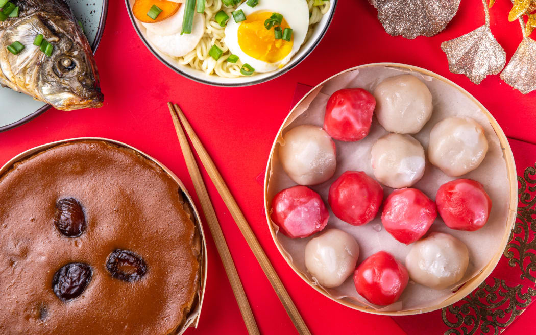 Traditional Chinese lunar New Year dinner table, party invitation, menu background with pork, fried fish, chicken, rice balls, dumplings, fortune cookie, nian gao cake, noodles, chinese decorations
