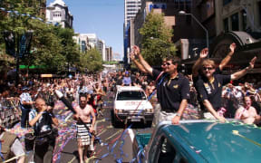 Russell Coutts (2/R) waves to the hundreds of thousands of specatators who turned up for a ticker-tape parade before the America's Cup is presented to Team New Zealand in Auckland, 04 March 2000