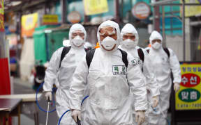 South Korean soldiers wearing protective gear spray disinfectant as part of preventive measures against the spread of the COVID-19 coronavirus, at a market in Daegu.