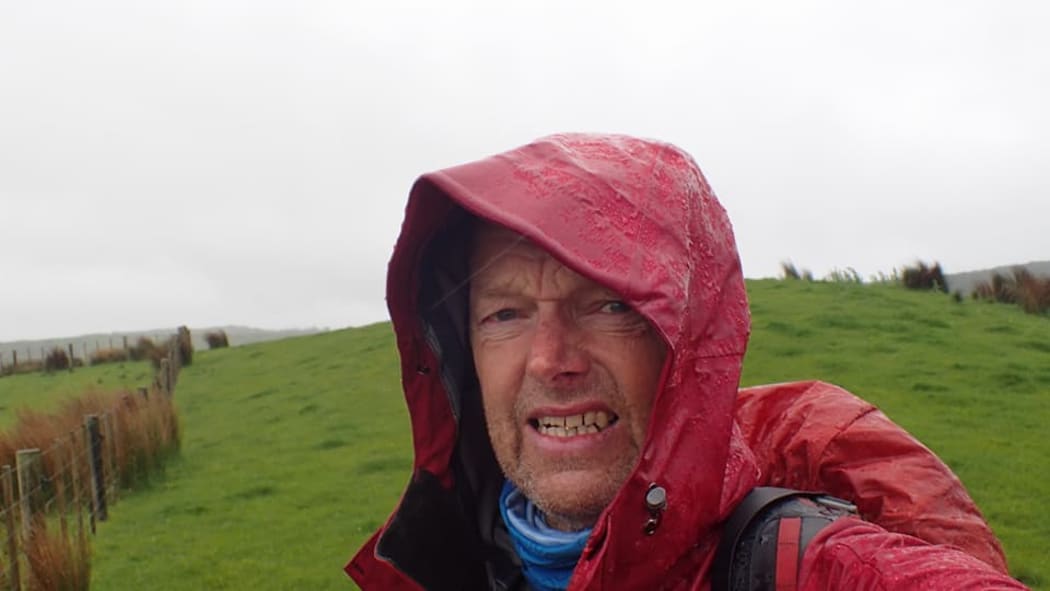 A head and shoulders shot of Bruce Hopkins huddling in his rain jacket.