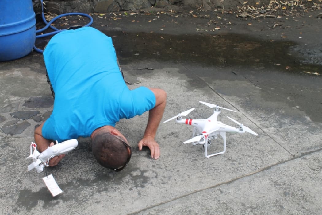 An image of Club Patrol Captain Matt Wade, kneeling down and closely inspecting the drone prior to takeoff.