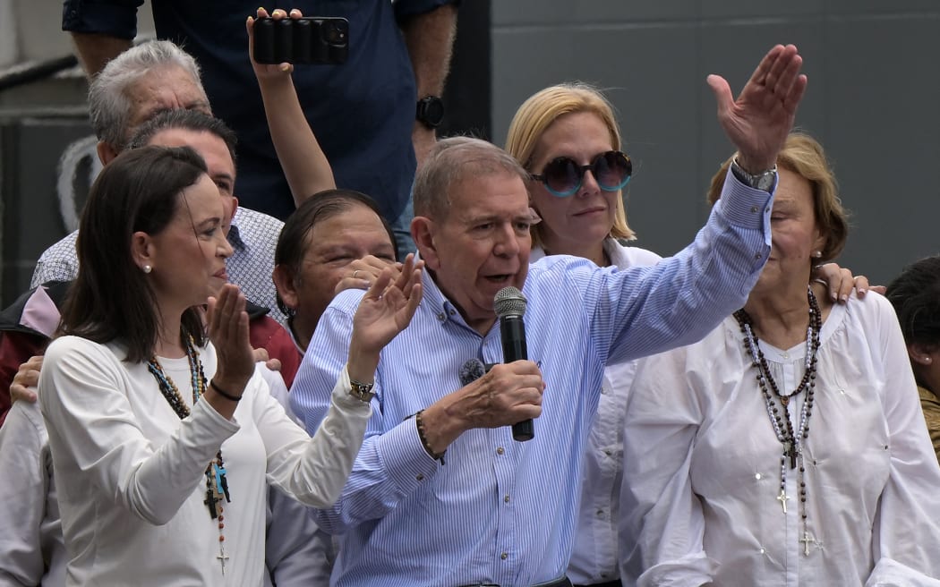 Venezuelan opposition presidential candidate Edmundo Gonzalez Urrutia talks to supporters as Venezuelan opposition leader Maria Corina Machado (L), his wife Mercedes Lopez (R) and his daughter Mariana Gonzalez (2nd R) listen during a rally in front of the United Nations headquarters in Caracas on July 30, 2024. Venezuela braced for new demonstrations on July 30, after four people died and dozens were injured when the authorities broke up protests against President Nicolas Maduro's claim of victory in the country's hotly disputed weekend election. (Photo by Yuri CORTEZ / AFP)