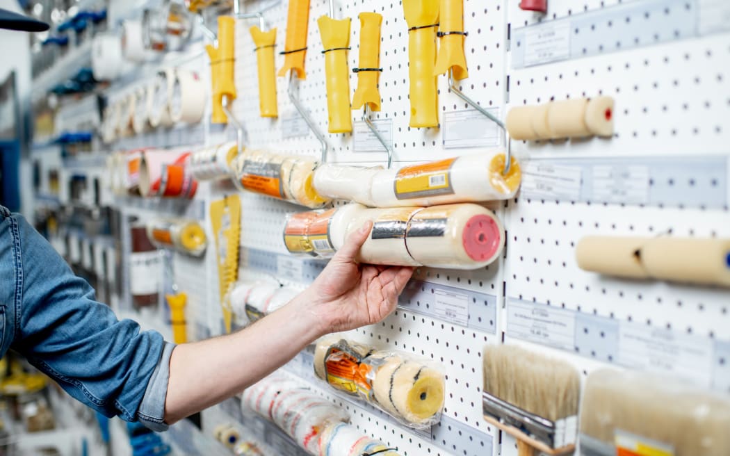 Workman choosing tools for painting in the building shop, close-up view - hardware store
