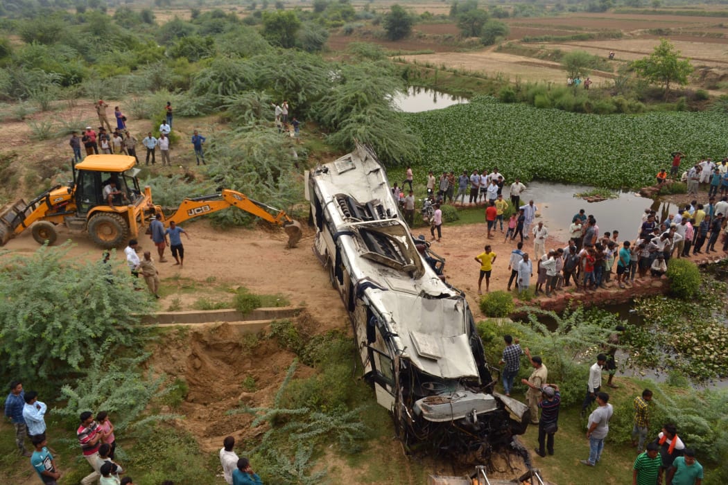 Onlookers and Indian police gather around the crumpled remains of a bus that crashed on the Delhi-Agra expressway, near Agra.