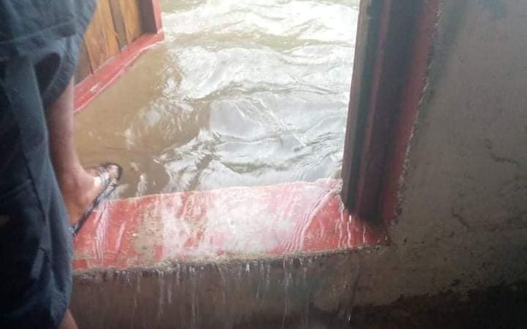 A man in Losap Island in the Upper Mortlocks section of Chuuk, Micronesia watches as ocean water rushes into his house.