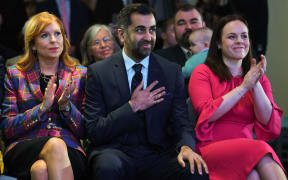 Scottish National Party (SNP) leadership candidates Ash Regan (L) and Kate Forbes (R) applaud as Humza Yousaf (C) reacts as he hears he has won the the SNP Leadership election vote, during the result announcement at Murrayfield Stadium in Edinburgh on March 27, 2023.