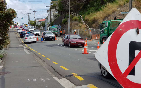 A street with lots of road cones and traffic.