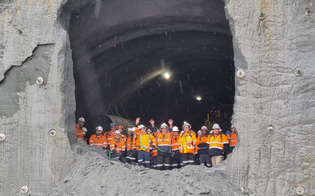 Workers peer down from the 235m tunnel after breaking through.
