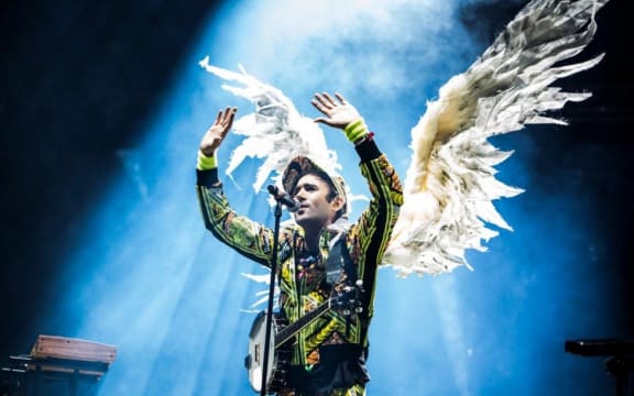 Sufjian Stevens performs on stage wearing large angel wings