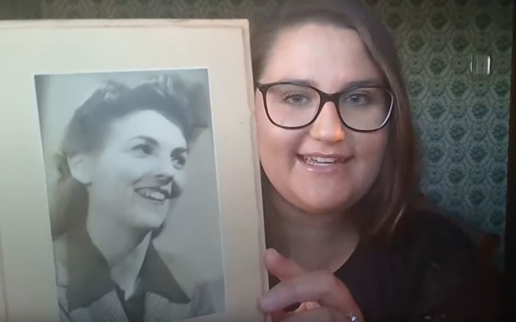 Caitlin Thompson holding the photo of a woman that she discovered tucked behind wallpaper in her Dunedin house.