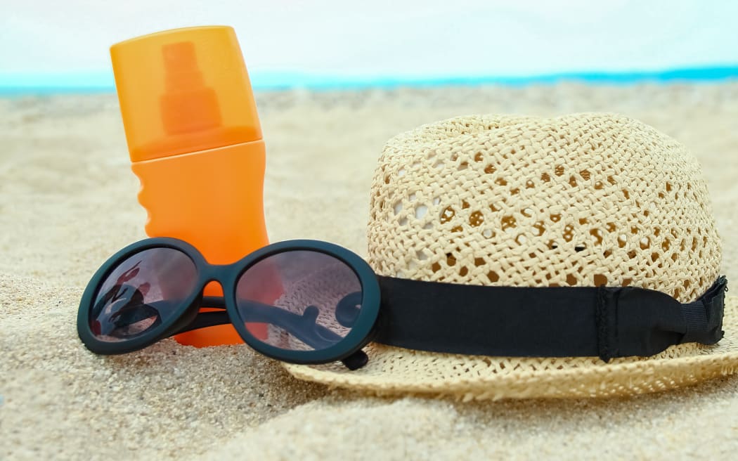 beautiful hat with glasses and cream on the sea in the sand background