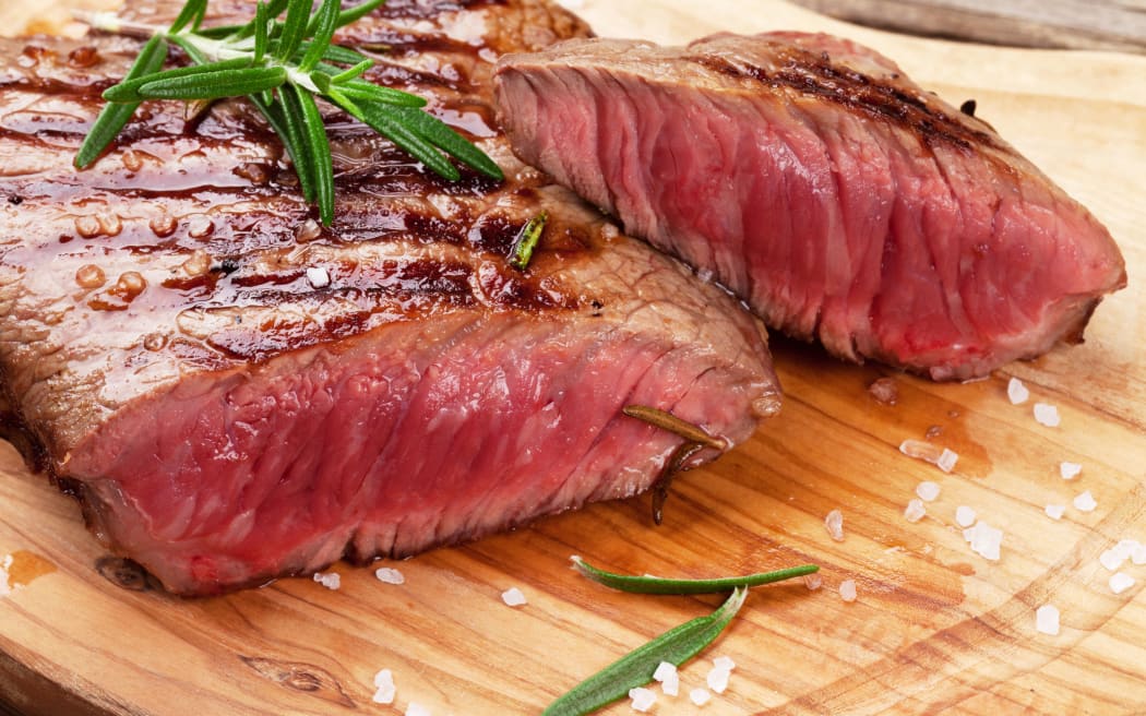 50344317 - grilled beef steak with rosemary, salt and pepper on cutting board