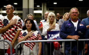 Supporters of Donald Trump stand for the Pledge of Allegiance as they wait for Trump's arrival at a rally at the Charlotte Convention Center.