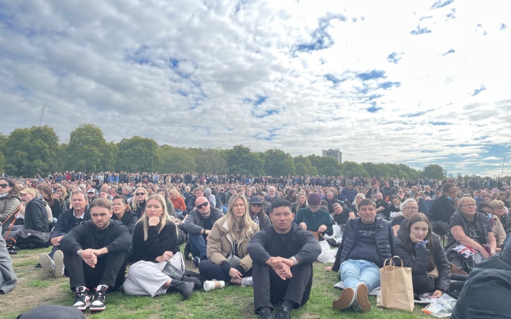 Hushed crowds at Hyde Park watch the funeral service of Queen Elizabeth II on a large screen.