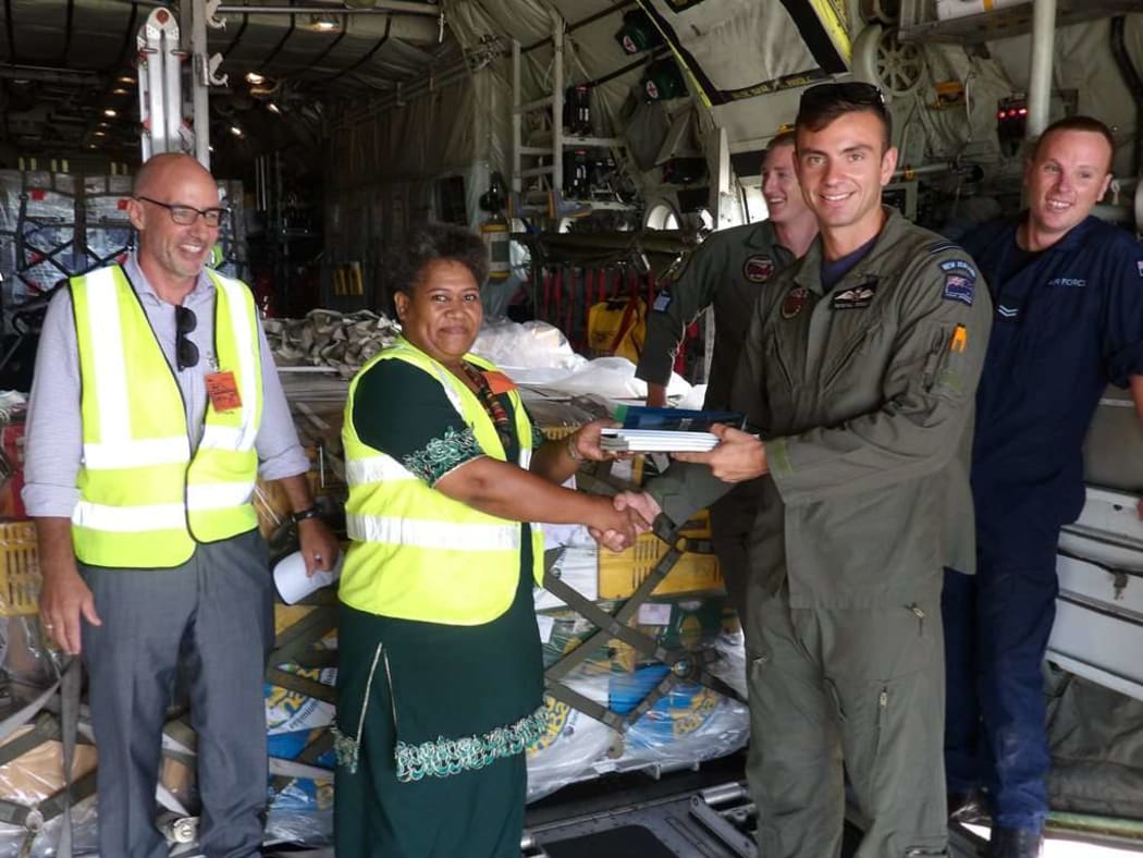 Flight Lieutenant Kendall Dooley, the captain of the Royal New Zealand Air Force hands over the textbooks to Merewalesi Vueti, the Director of Library Services in Fiji’s Ministry of Education, as New Zealand High Commissioner to Fiji Mark Ramsden (left) looks on.
