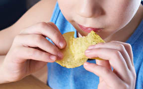 Little boy eating potato chips.