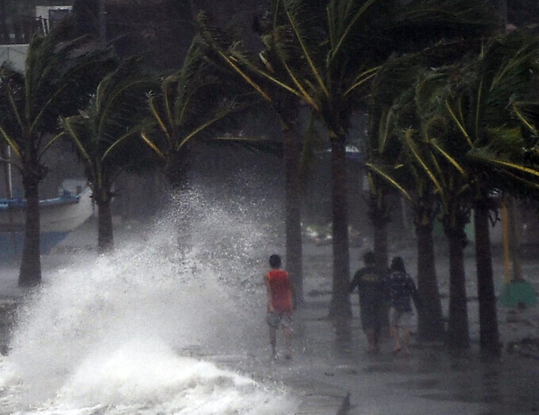 Residents walking past high waves brought about by strong winds pounding the seawall.