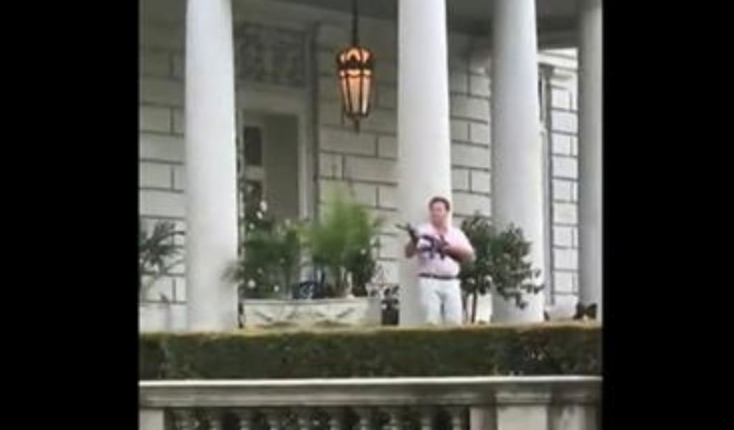 This screen grab taken from a video shows Mark McCloskey, 63, and his 61-year-old wife, Patricia, standing outside their home and holding guns including a semi-automatic rifle at Black Lives Matter protesters.