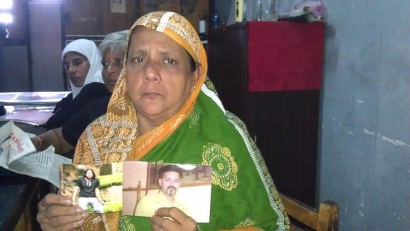 A Sri Lankan woman holds pictures of her missing son.