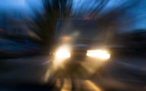 A vehicle approaches in semi-darkness under dangerous conditions.