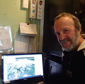 Department of Conservation volcanology advisor Harry Keys sits next to the Eruption Detection System that interprets potential volcanic hazards on Mount Ruapehu and sets off public warnings