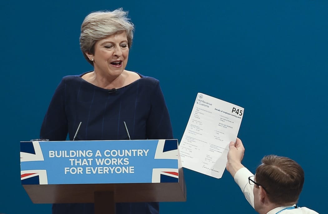 Comedian Simon Brodkin gives a mock P45 (employee leaving form) to Britain's Prime Minister Theresa May during her speech on the final day of the Conservative Party annual conference.