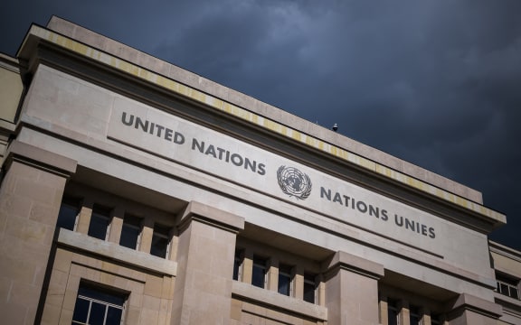 A picture taken on September 15, 2025 shows a sign of the United Nations under dark clouds on a building of the "Palais des Nations", which houses the UN Offices in Geneva.