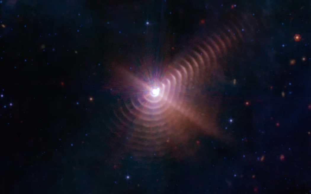The two stars in Wolf-Rayet 140 produce shells of dust every eight years that look like rings, as seen in this image from NASA’s James Webb Space Telescope. Each ring was created when the stars came close together and their stellar winds collided, compressing the gas and forming dust.