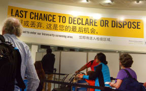 Passengers under Biosecurity sign in Auckland Airport.