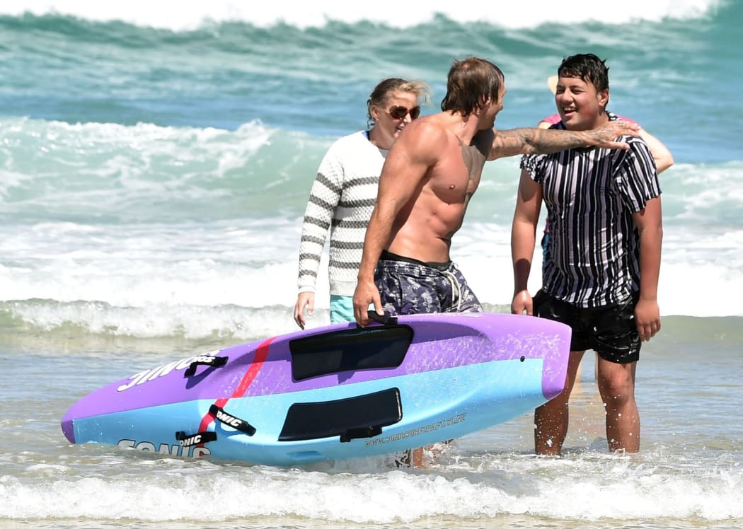 Rob Ratten on the left puts his arm on the shoulder of a member of the public he rescued at St Kilda beach on Monday afternoon.