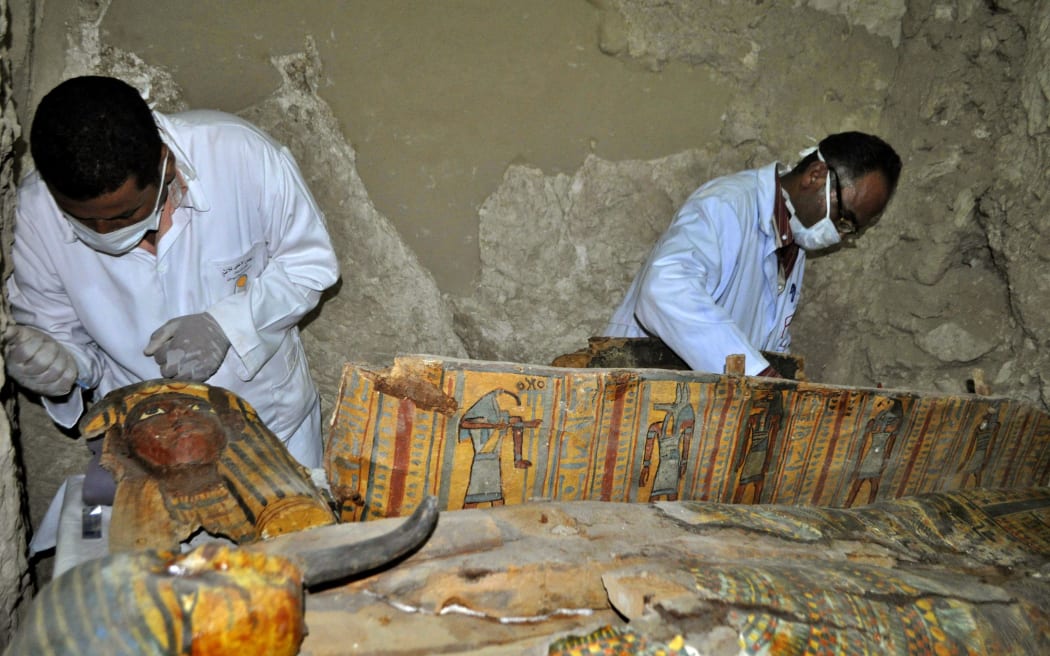 Members of an Egyptian archaeological team work on a wooden coffin discovered in a 3,500-year-old tomb in the Draa Abul Nagaa necropolis, near the southern Egyptian city of Luxor,