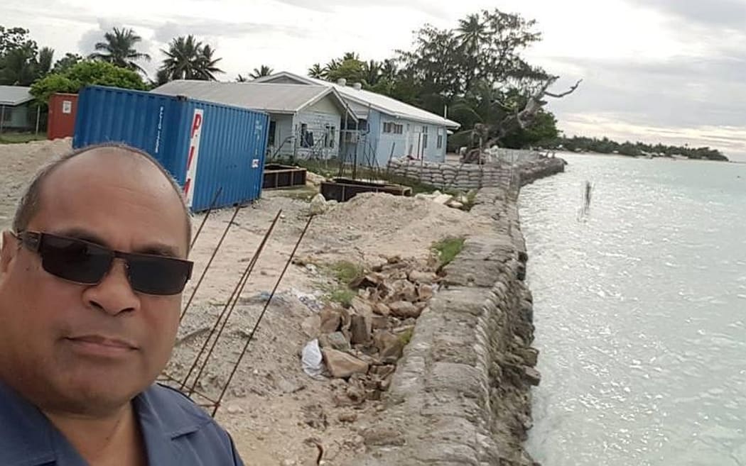 MP in selfie on coast line with houses in the background