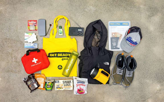 A range of essential items to include in evacuation bags including a water-proof jacket, water, first aid kit, medication, snacks, passport, walking shoes, a hat and torch.