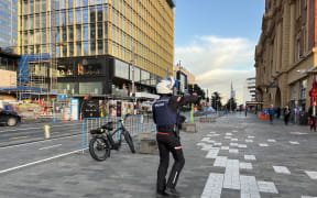 A police officer directs people away from an incident at Quay Street in Auckland's CBD.