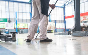 mechanic in auto repair center Cleaning using a mop Squeeze water from the epoxy floor. in the car repair service center