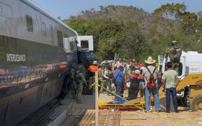 Mexican Army soldiers and Civil Protection members rescue passengers from the Interoceanic train that derailed in the Asuncion Ixtaltepec area on the route to Oaxaca, Mexico, on December 28, 2025. At least 20 people were injured this Sunday after a train crashed in the state of Oaxaca, in southern Mexico, authorities reported. (Photo by Rusvel RASGADO / AFP)