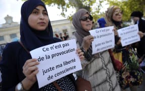 Women hold signs reading "Is it not a provocation, just my freedom of conscience" during a "headscarf march" in Avignon, southern France.
