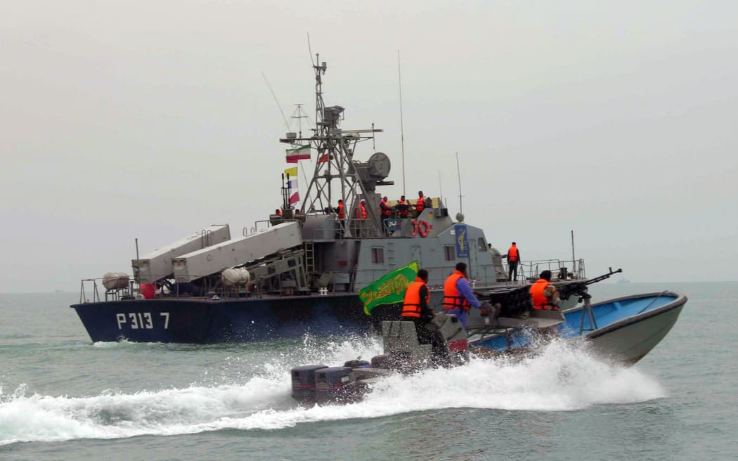 A picture released by the official Iranian News Agency shows members of Iran's elite Revolutionary Guard riding their boat along with an Iranian naval vessel during manoeuvers along the Gulf Sea and Sea of Oman, 03 April 2006.