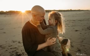 Samantha McConnell sits on a beach with her young daughter.