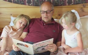 Jack Saprunoff, reading to grandchildren Ivy (left) and Zosia Costello.