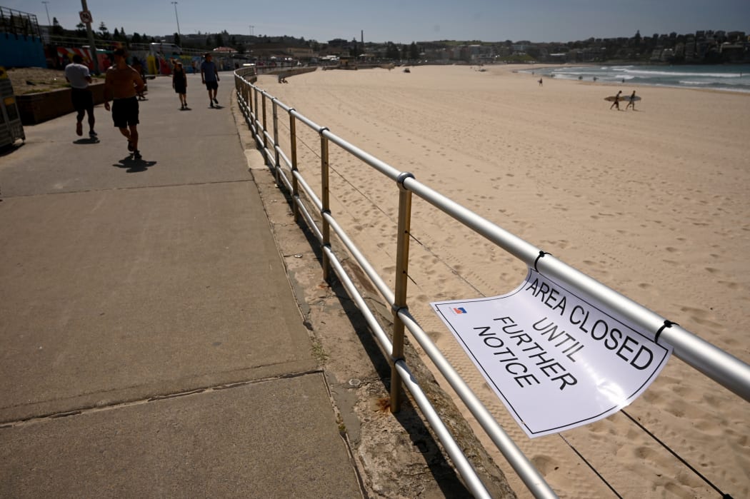 People walk past an empty Bondi Beach after authorities closed Sydney's most popular beach on March 22, 2020. Bondi Beach was closed after huge crowds flocked to the popular sunbathing spot despite a government ban on large gatherings due to the coronavirus pandemic.