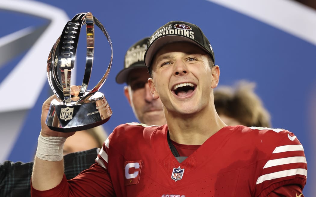 Brock Purdy #13 of the San Francisco 49ers reacts as he holds the George Halas Trophy after defeating the Detroit Lions 34-31 in the NFC Championship Game.