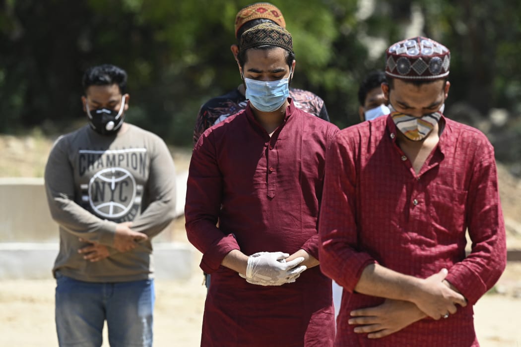 Relatives and friends offer a prayer during the funeral of a Covid-19 coronavirus victim at a graveyard in New Delhi on April 3, 2021. (Photo by Sajjad HUSSAIN / AFP)