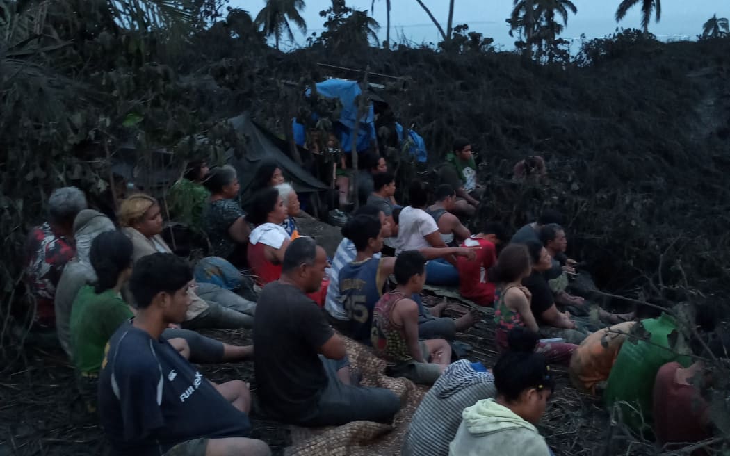 This handout photo taken on January 16, 2022 and received on January 25 courtesy of Rev. Kisini Toetu'u via Matangi Tonga shows survivors praying on a hilltop at dawn on Mango Island, following the January 15 eruption of the nearby Hunga Tonga-Hunga Ha'apai underwater volcano.
