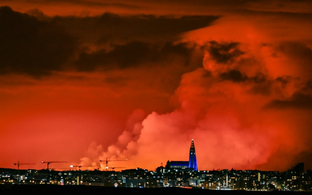 The skyline of Reykjavik is against the backdrop of orange coloured sky due to molten lava flowing out from a fissure on the Reykjanes peninsula north of the evacuated town of Grindavik, western Iceland on March 16, 2024. Lava spewed Saturday from a new volcanic fissure on Iceland's Reykjanes peninsula, the fourth eruption to hit the area since December, authorities said. (Photo by Halldor KOLBEINS / AFP)