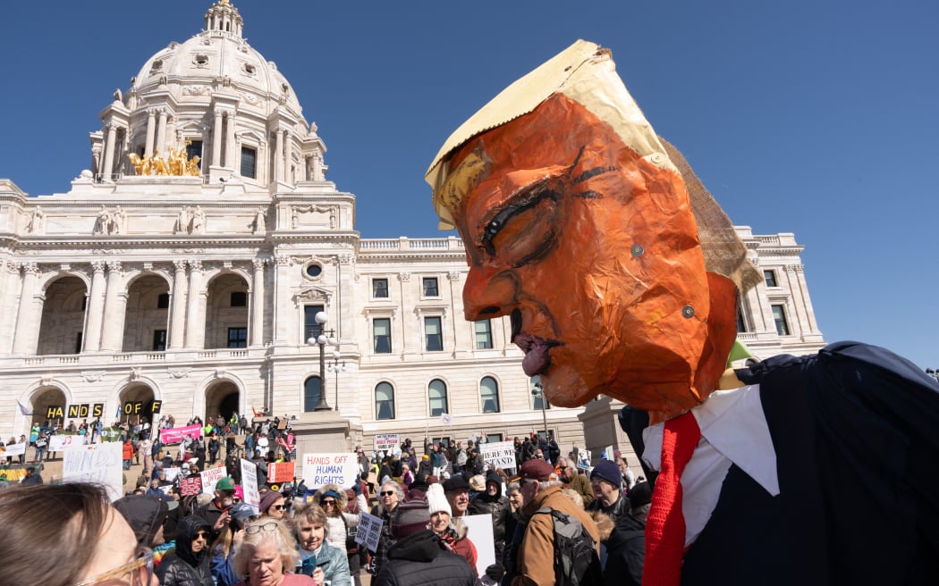 A demonstrator carries a large papier mache likeness of US President Donald Trump outside the Minnesota State Capitol during the nationwide 'Hands Off!' protest against Trump and his advisor, Tesla CEO Elon Musk, in St. Paul, Minnesota.